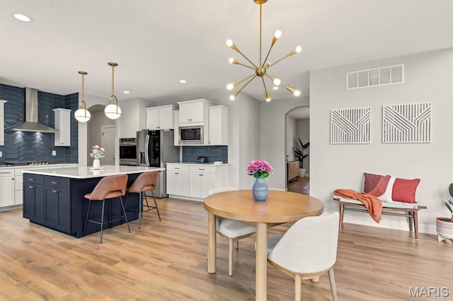 215 Everett Creek Ct, Lake St Louis, MO 63367 - dining area featuring arched walkways, light wood-style flooring, a chandelier, and recessed lighting