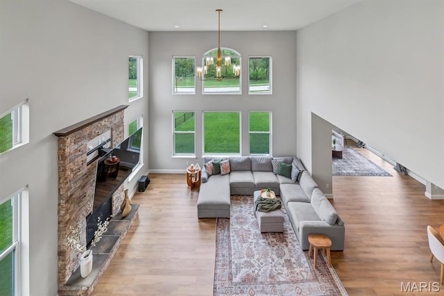 215 Everett Creek Ct, Lake St Louis, MO 63367 - living area with a stone fireplace, plenty of natural light, a chandelier, wood finished floors, and a high ceiling