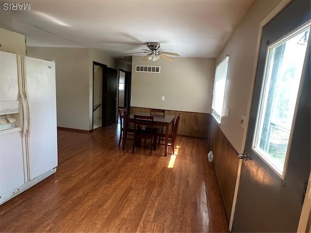dining space featuring a wainscoted wall, wood finished floors, ceiling fan, and wooden walls