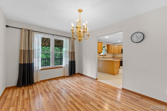 2305 Loretta Ln, Collinsville, IL 62234 - unfurnished dining area with light wood-style flooring, a chandelier, baseboards, a sink, and a textured ceiling