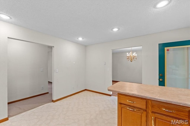 2305 Loretta Ln, Collinsville, IL 62234 - kitchen with a textured ceiling, brown cabinets, light countertops, baseboards, and a chandelier