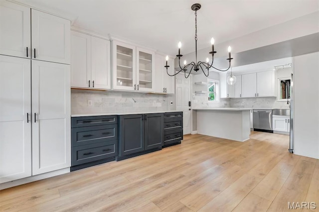 kitchen with stainless steel dishwasher, white cabinets, light countertops, and a chandelier