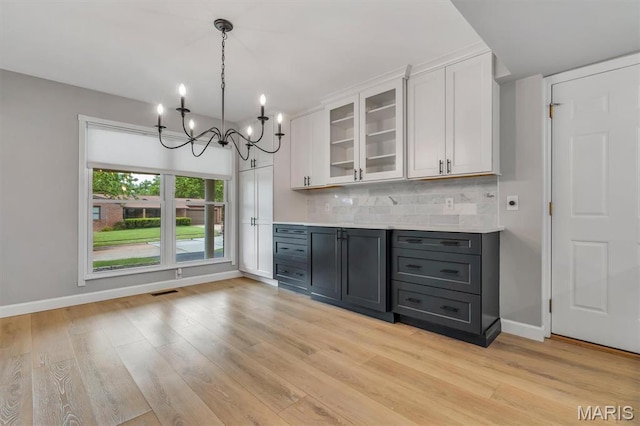 kitchen featuring white cabinets, light wood-type flooring, backsplash, and light countertops