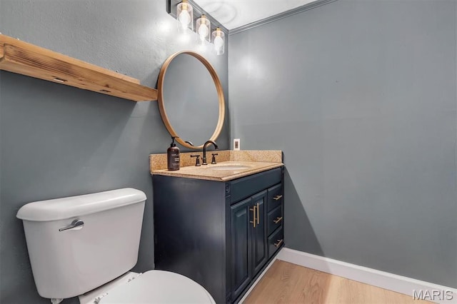 half bathroom with wood finished floors, toilet, vanity, and baseboards