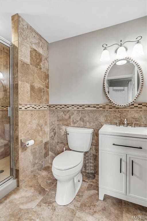 bathroom with a shower stall, vanity, toilet, and tile walls
