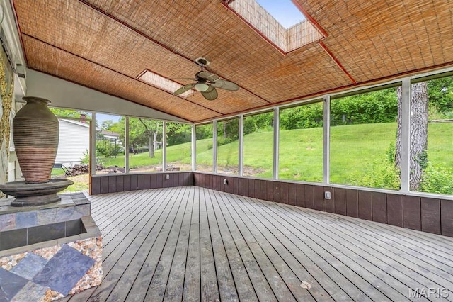 unfurnished sunroom with a ceiling fan, a skylight, and lofted ceiling