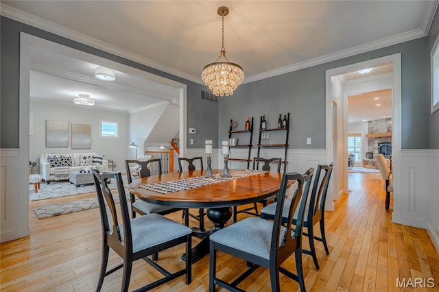 734 Fuhrmann Ter, Glendale, MO 63122 - dining area featuring light wood-style floors, wainscoting, plenty of natural light, a stone fireplace, and a chandelier