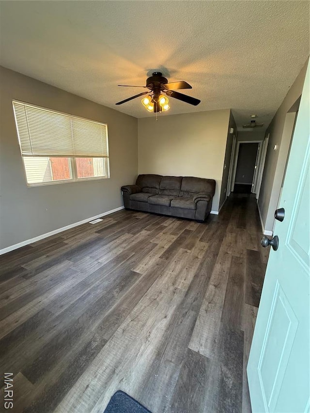 unfurnished living room featuring ceiling fan, dark wood-style flooring, baseboards, and a textured ceiling