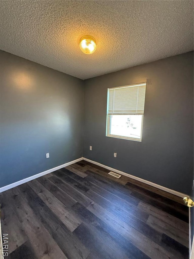 spare room with dark wood-style flooring, baseboards, and a textured ceiling