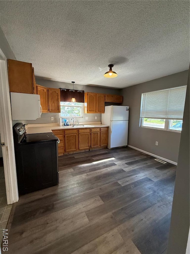 kitchen featuring white appliances, healthy amount of natural light, dark wood-style flooring, baseboards, and a textured ceiling
