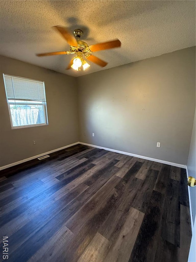 spare room with ceiling fan, dark wood finished floors, baseboards, and a textured ceiling