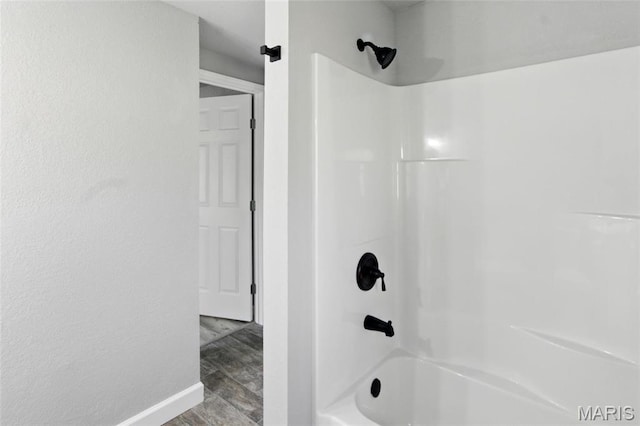 619 E 3rd St, De Soto, MO 63020 - full bathroom featuring washtub / shower combination, wood finished floors, and baseboards