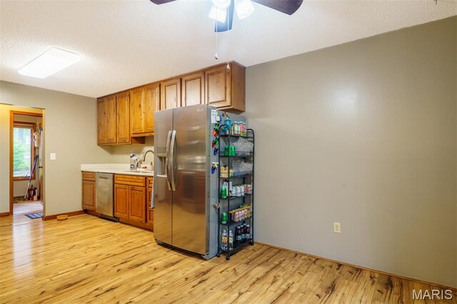 10280 County Road 3110, Rolla, MO 65401 - kitchen with appliances with stainless steel finishes, light wood-style flooring, a ceiling fan, a sink, and brown cabinetry