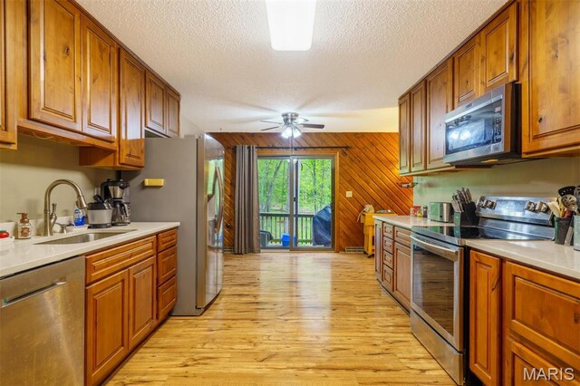 10280 County Road 3110, Rolla, MO 65401 - kitchen featuring stainless steel appliances, a sink, brown cabinets, light wood-style flooring, and a textured ceiling