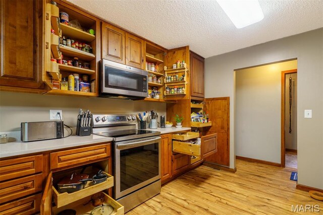 10280 County Road 3110, Rolla, MO 65401 - kitchen featuring stainless steel appliances, open shelves, light countertops, light wood-style flooring, and a textured ceiling