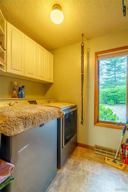 10280 County Road 3110, Rolla, MO 65401 - laundry area featuring cabinet space, washer and dryer, baseboards, and a textured ceiling