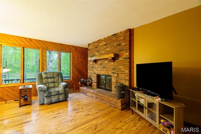 10280 County Road 3110, Rolla, MO 65401 - living room featuring a textured ceiling, a fireplace, wood finished floors, and wooden walls