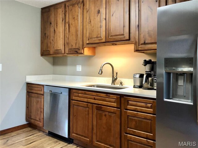10280 County Road 3110, Rolla, MO 65401 - kitchen with stainless steel appliances, a sink, light wood finished floors, light countertops, and brown cabinets