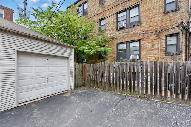 garage featuring driveway and fence