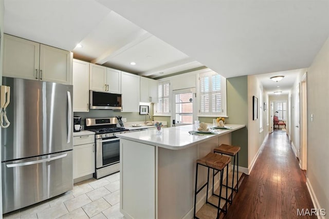 kitchen with stainless steel appliances, a breakfast bar area, light countertops, plenty of natural light, and recessed lighting