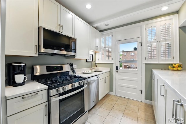 kitchen with appliances with stainless steel finishes, a sink, light countertops, white cabinetry, and recessed lighting