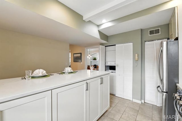 kitchen with freestanding refrigerator, light tile patterned floors, white cabinets, and light countertops