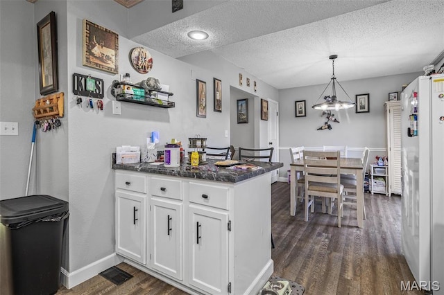 809 Cottage Rd, Bonne Terre, MO 63628 - kitchen featuring dark wood-style floors, white cabinets, dark countertops, a peninsula, and freestanding refrigerator