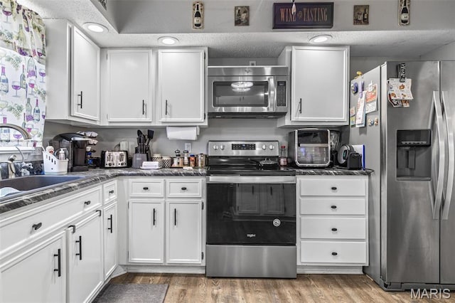 809 Cottage Rd, Bonne Terre, MO 63628 - kitchen with appliances with stainless steel finishes, white cabinets, light wood-type flooring, and a sink