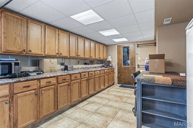 809 Cottage Rd, Bonne Terre, MO 63628 - kitchen with brown cabinets, a drop ceiling, stainless steel microwave, open shelves, and light tile patterned floors