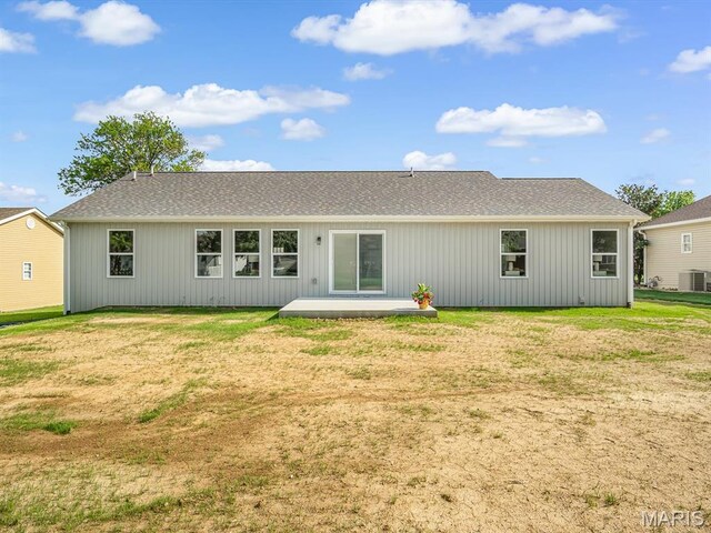 rear view of property featuring a lawn, a patio, and roof with shingles