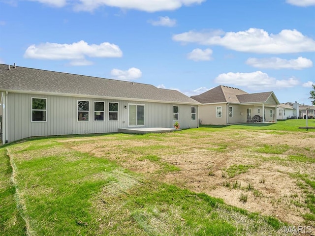 rear view of house with a patio, a yard, and a shingled roof