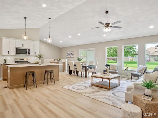living area with light wood-style floors, vaulted ceiling, recessed lighting, and a ceiling fan