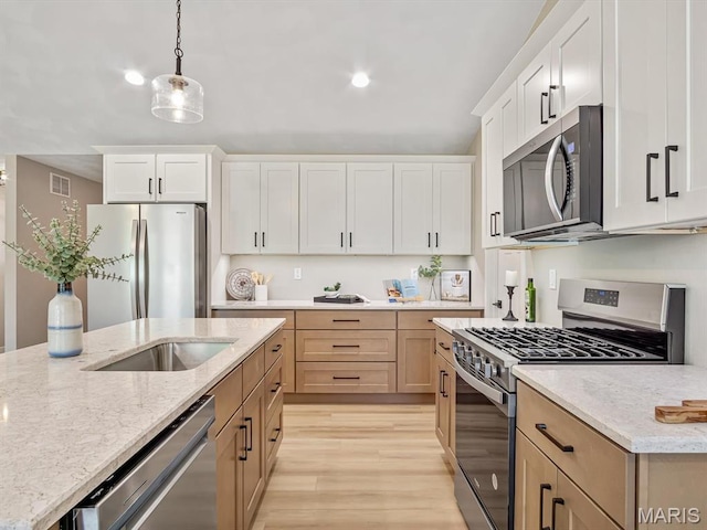 kitchen with appliances with stainless steel finishes, light wood finished floors, decorative light fixtures, light stone counters, and recessed lighting