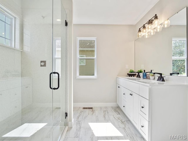 full bath with double vanity, a shower stall, marble finish flooring, and baseboards