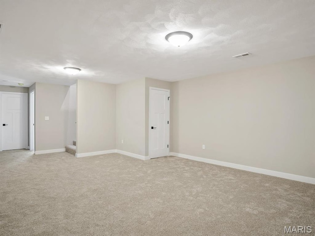 spare room with light carpet, baseboards, and stairway