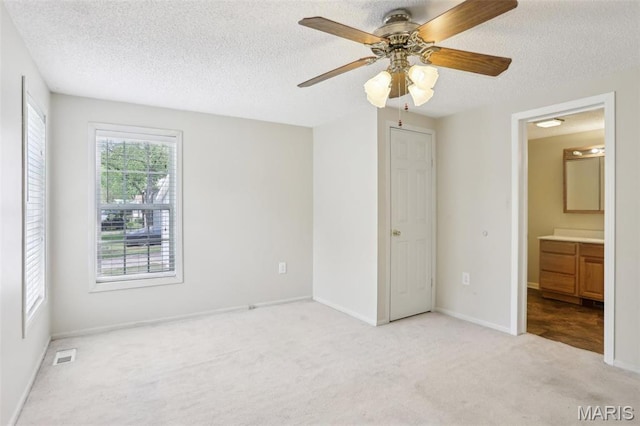 21839 Dove Ln, Carlyle, IL 62231 - unfurnished bedroom with light carpet, a textured ceiling, baseboards, connected bathroom, and ceiling fan