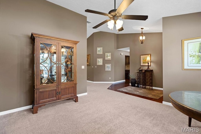 foyer entrance with vaulted ceiling, baseboards, a ceiling fan, and light colored carpet