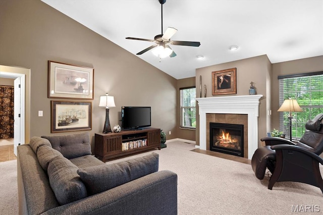 living room with carpet, lofted ceiling, a ceiling fan, a tiled fireplace, and baseboards