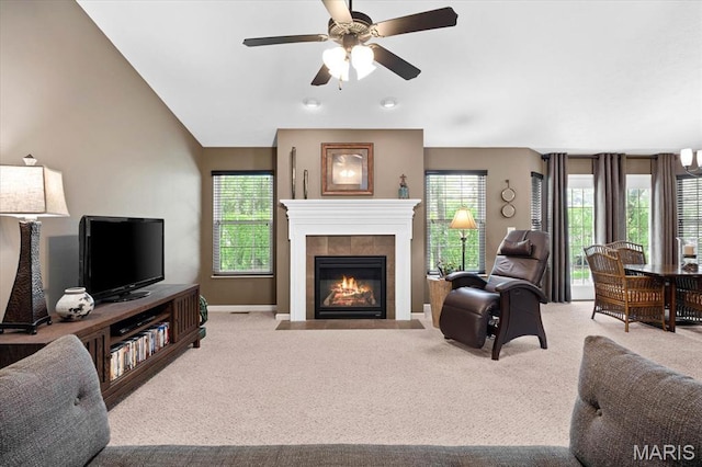 carpeted living room featuring ceiling fan, a tiled fireplace, and baseboards