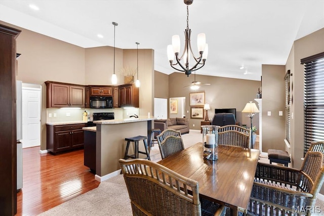 carpeted dining room featuring a chandelier, high vaulted ceiling, baseboards, a ceiling fan, and wood finished floors