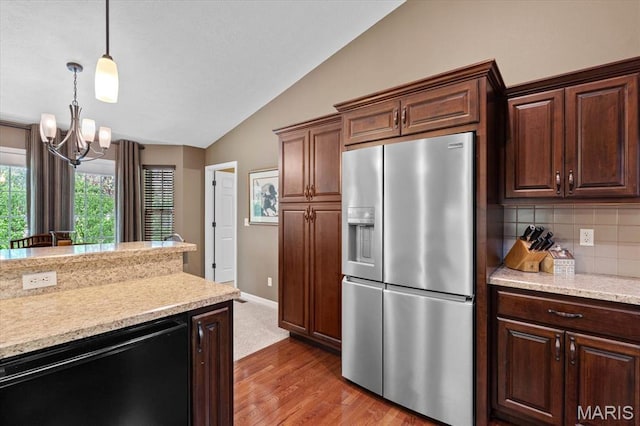 kitchen with stainless steel fridge, lofted ceiling, a chandelier, wood finished floors, and backsplash
