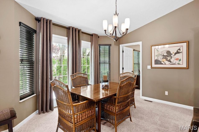 dining room with a chandelier, light colored carpet, baseboards, and lofted ceiling