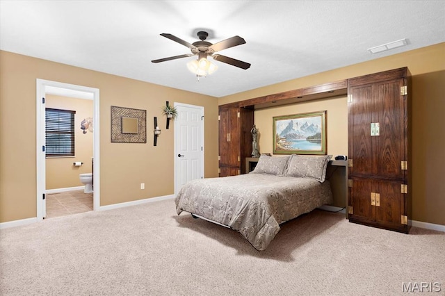 bedroom with light carpet, baseboards, ensuite bathroom, and a ceiling fan