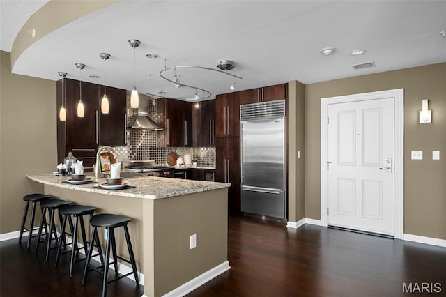 4909 Laclede Ave Unit 805, Saint Louis, MO 63108 - kitchen with stainless steel built in refrigerator, wall chimney exhaust hood, a peninsula, dark wood-type flooring, and a kitchen bar