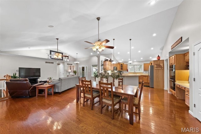 dining space with a ceiling fan, wood finished floors, and high vaulted ceiling