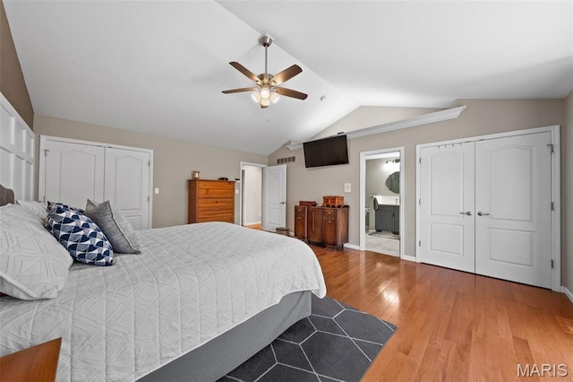 bedroom with vaulted ceiling, wood finished floors, baseboards, ceiling fan, and ensuite bath