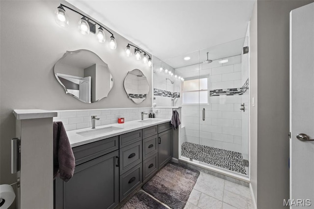 bathroom featuring a shower stall, double vanity, and tile patterned flooring