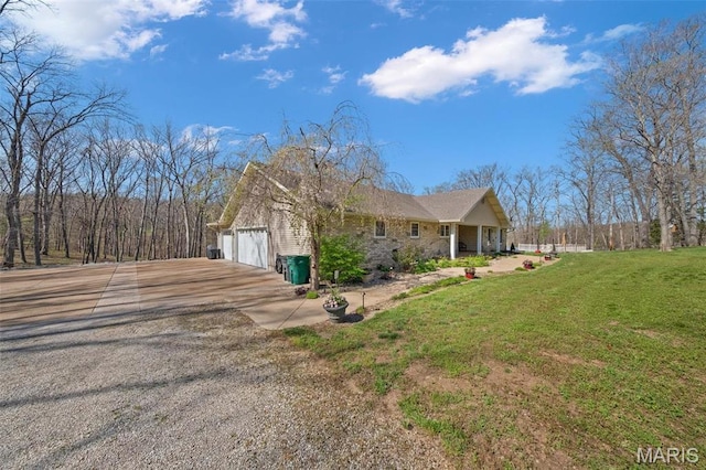 view of side of home with gravel driveway and a lawn