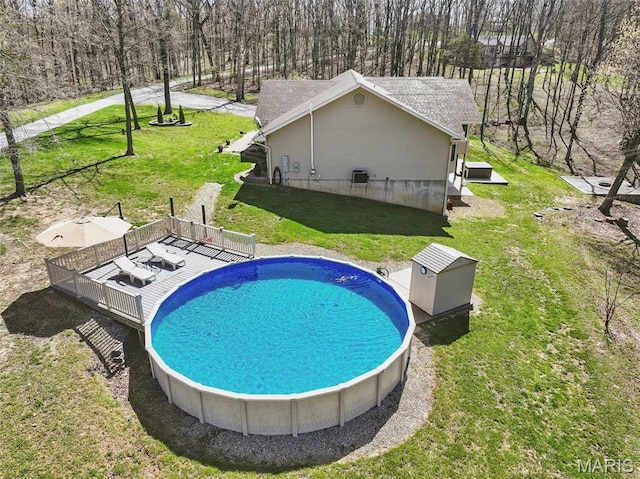 outdoor pool featuring a wooden deck and a lawn