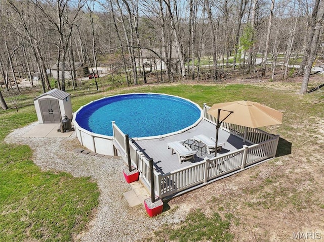 outdoor pool featuring a storage shed, an outdoor structure, a wooden deck, and a lawn